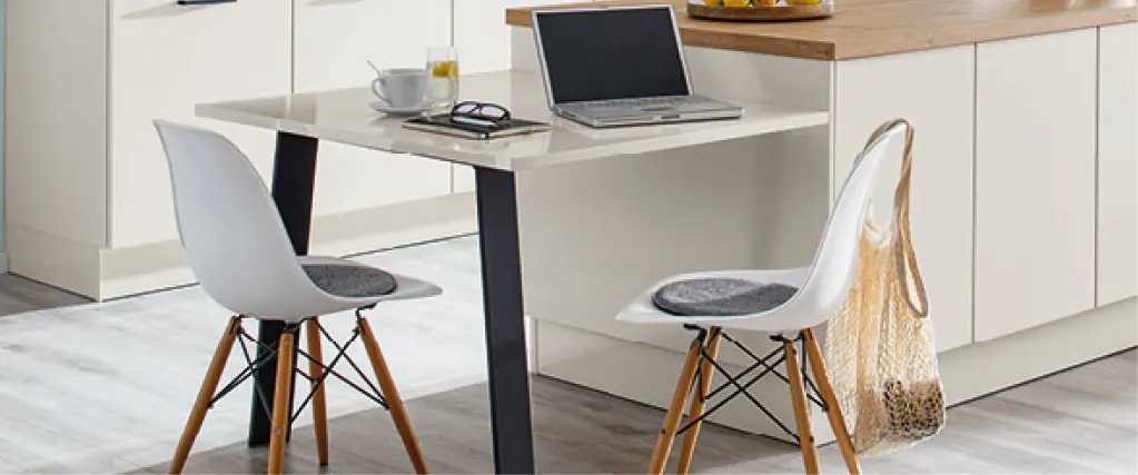 Helle Wohnküche mit weißer Küchenzeile, Holzarbeitsplatten und Kücheninsel mit Sitzplätzen, Laptop und Obstschale, ideal für Kochen, Arbeiten und gemeinsames Wohnen im modernen Küchenstil.